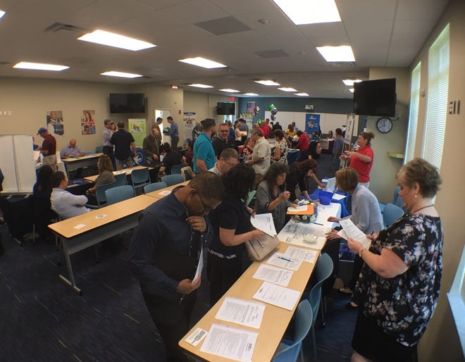 Job seekers look over the available positions at the Palm Coast Data table during the 6th annual Flagler County Job Fair on Friday. Organizers said 58 employers registered to set up tables for this year's fair on the Palm Coast campus of Daytona State College. [News-Journal/Aaron London]