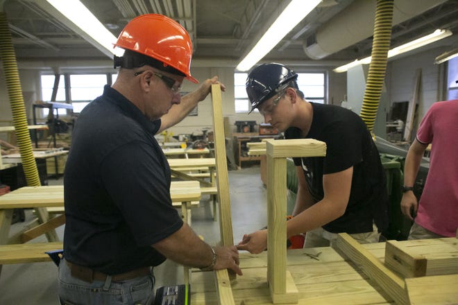 Instructor Dan McAuley helps student Kasey Martin put the legs on a picnic table during Construction Academy at Leesburg High School. [Cindy Sharp/Correspondent]