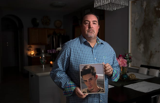Rob Rivard poses with a photo of his stepson Chris Machesney on Jan. 4, 2019 at his home in Tampa. Machesney died by suicide in November 2018 when he jumped from the Sunshine Skyway Bridge. There were a record number of suicides from the Skyway bridge in 2018. (Monica Herndon/Tampa Bay Times via AP)