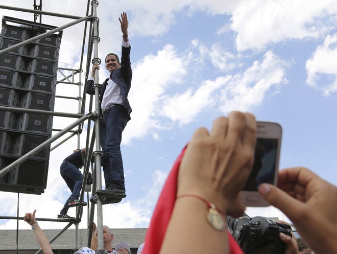 Venezuelan Congress President Juan Guaido, an opposition leader who declared himself interim president, waves from the scaffolding after speaking at a rally demanding the resignation of Venezuelan President Nicolas Maduro in Caracas, Venezuela, Monday. The United States and about 50 other countries recognize Guaido as the rightful president of Venezuela, while Maduro says he is the target of a U.S.-backed coup plot. [Fernando Llano/AP Photo]