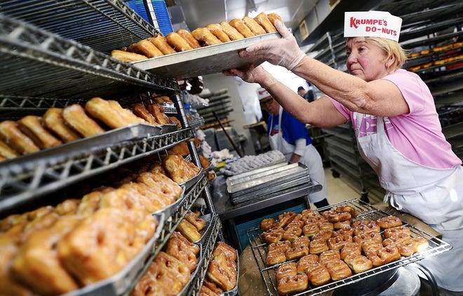 Clara Krumpe stacks freshly made fastnachts at Krumpe's Do-Nut Shop in Hagerstown, Md., Tuesday, March 5, 2019. A steady stream of customers stopped in to buy glazed, cinnamon or powderd fastnachts to celebrate the Pennsylvania Dutch tradition that falls on the Tuesday before Ash Wednesday. [Colleen McGrath/The Herald-Mail via AP]