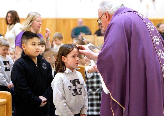 St. Edward School student Lily Gerba receives ashes from Father Rod Kreidler while Kayden Le waits in line during the afternoon Ash Wednesday service at St. Edward Church in Ashland. Ash Wednesday is a Christian holy day of prayer, fasting and repentance. It falls on the first day of Lent, the six weeks of penitence before Easter. Ash Wednesday derives its name from the placing of repentance ashes on the foreheads of participants. The ashes are often prepared by burning palm leaves from the previous year's Palm Sunday observances.