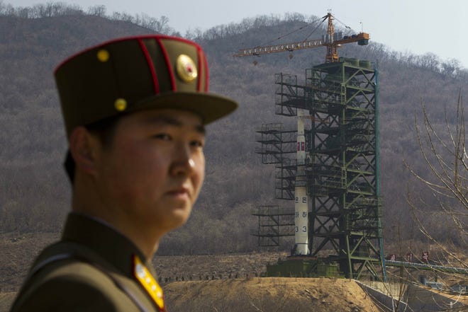 A soldier stands in front of the Unha-3 rocket at a launching site in Tongchang-ri, North Korea. North Korea is reportedly restoring facilities at its long-range rocket launch site that it had dismantled as part of disarmament steps last year. A major South Korean newspaper reports that the country's spy service gave such an assessment to lawmakers in a private briefing on Tuesday. [David Guttenfelder/AP Photo]