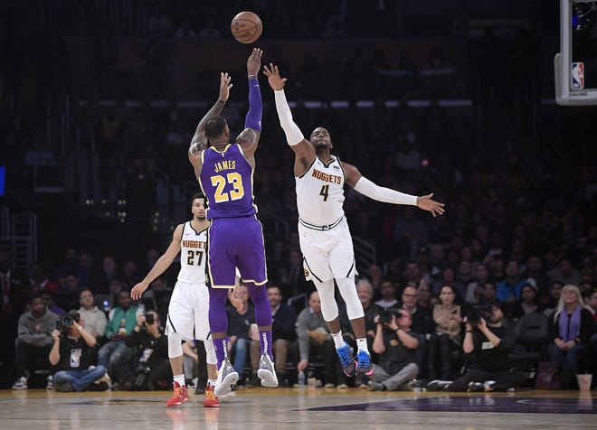 Los Angeles Lakers forward LeBron James (23) shoots as Denver Nuggets forward Paul Millsap, right, defends while guard Jamal Murray watches during the first half of an NBA basketball game Wednesday in Los Angeles. [MARK J. TERRILL/ASSOCIATED PRESS]