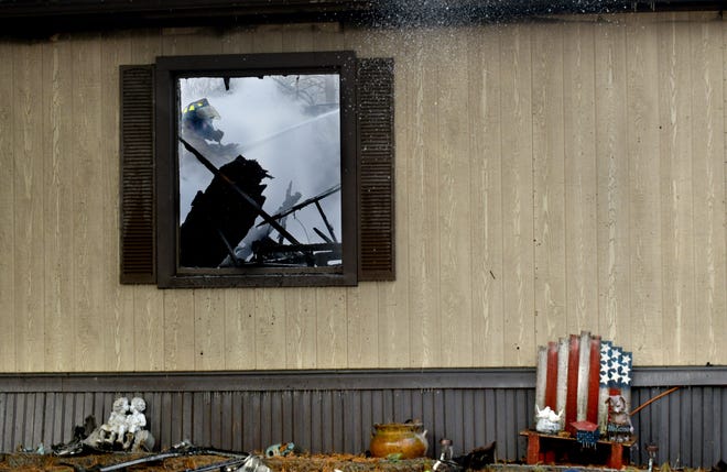 DAVID ZALAZNIK/JOURNAL STAR A Creve Coeur firefighter is visible through the window as he pours water on the inside of a double-wide mobile home that was declared a total loss in a Feb. 26 fire. There were no injuries in the early morning fire at 701 Fisher Road, Lot 267.