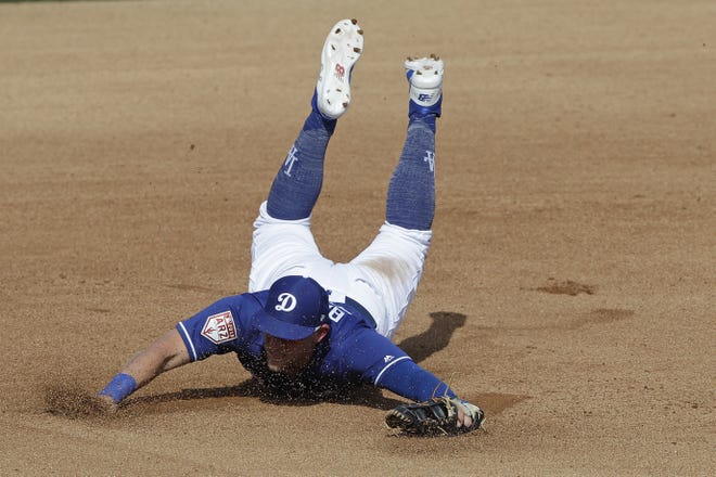 Los Angeles Dodgers' Matt Beaty dives for a ball hit by Los Angeles Angels' Wilfredo Tovar during the fourth inning of a spring training baseball game in Glendale, Ariz. [AP Photo/Darron Cummings, File]