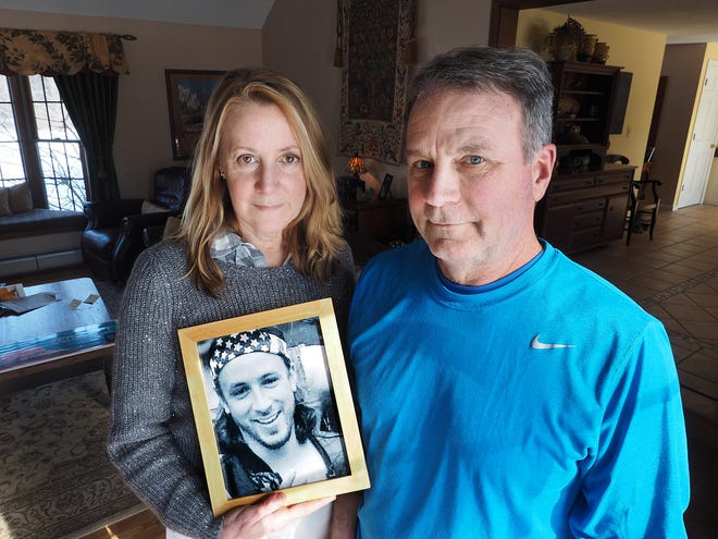 Jeanne and Jim Moser of East Kingston hold a photograph of their son Adam, who died of a fentanyl overdose in September 2015. The Mosers have launched an opioid awareness campaign called Zero Left, now in place at hospitals across New Hampshire, which helps residents dispose of unused opioids. [Rich Beauchesne/File Photo]
