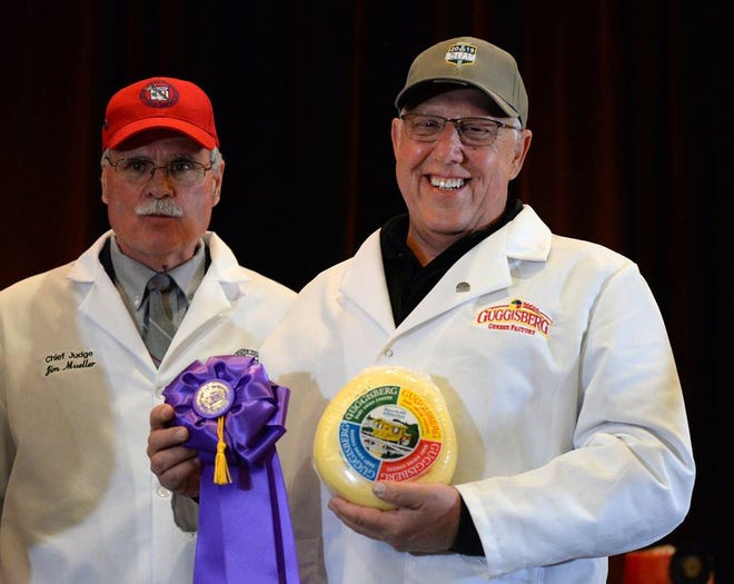 Richard Guggisberg, (right), president of Guggisberg Cheese in Charm, proudly displays a grand champion prize he was presented by one of the judges of the United States Championship Cheese contest in Green Bay, Wisconsin.