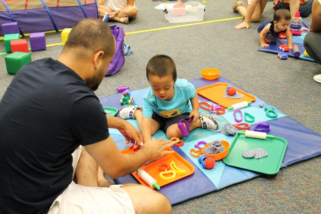A Father plays with his toddler son at one of Forty Carrots Family Center free library Partners in Play groups. [Submitted photo]