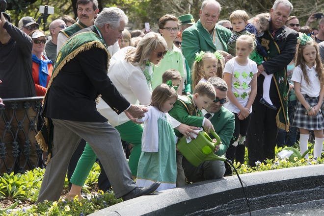 Savannah St. Patrick's Day Parade Committee Grand Marshal Jerry Counihan holds the hand of his granddaughter, Adri Counihan, 3, while his son Jeremy Counihan and daughter-in-law Haley Counihan help their son, Braeden Counihan, 5, pour green dye into the Forsyth Park Fountain on Friday. [Will Peebles/Savannahnow.com]