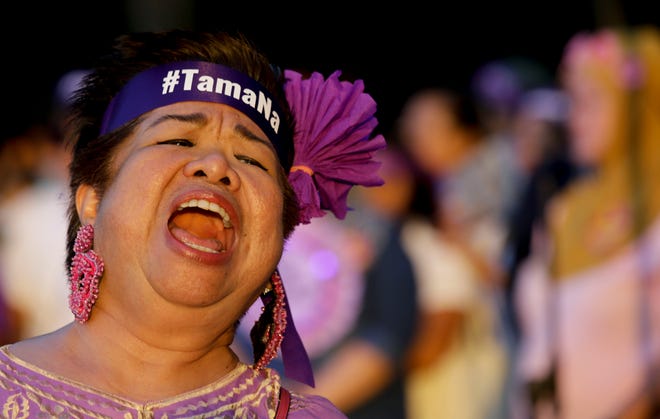 A woman activist wearing a headband with a sign that reads "enough" shouts slogans as their group marks International Women's Day in Manila, Philippines on Friday, March 8, 2019. The group criticized Philippine President Rodrigo Duterte, opposed martial law in Mindanao and called for equal rights. (AP Photo/Aaron Favila)