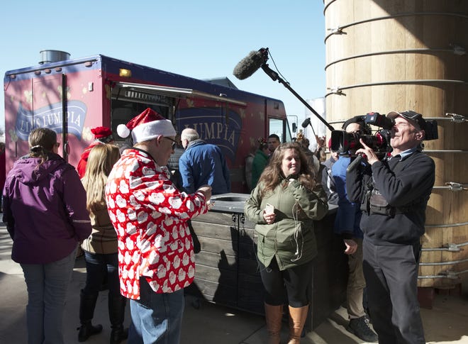 David Adams, dressed in Christmas attire for the holiday-themed finale of "Great Food Truck Race," is interviewed near the Lia's Lumpia truck at Newport Vineyards on Saturday. [Peter Silvia]