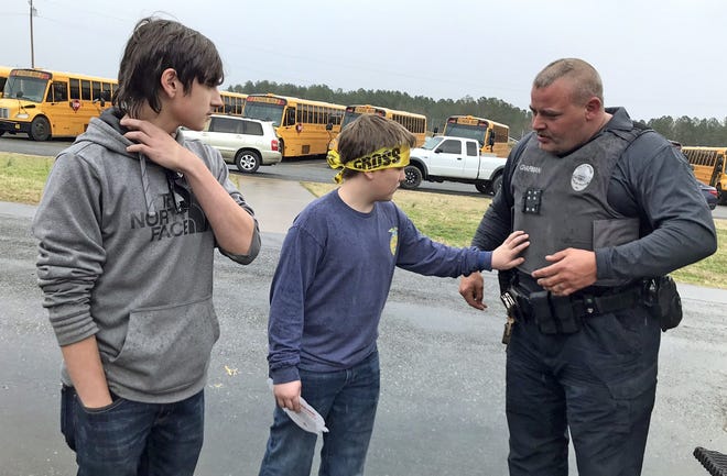 Mike Chapman of the Shelby Police Department shares information about his bulletproof vest with Cody Bowen, 14, and Micheal Callahan, 13, at Crest Middle School's job fair on Friday. [Brittany Randolph/The Star]
