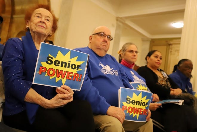 Members of Mass. Senior Action, including membership coordinator Joan Pingley and Bristol chapter acting president Bert Chretien, hold up "Senior Power!" signs Monday in the front row of a State House lobby day. [SAM DORAN/SHNS]