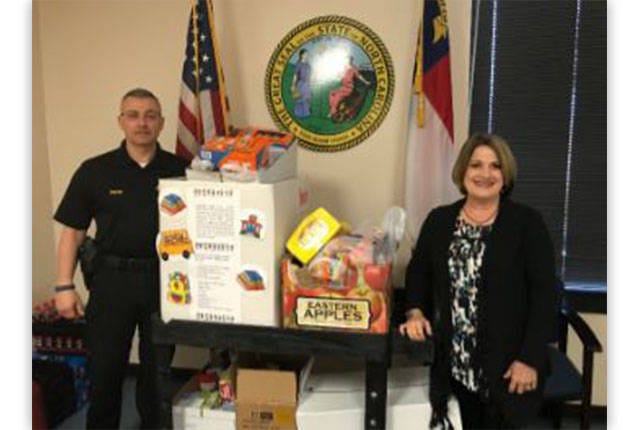 WHAT A PAL — Capt. Kevin Walton, with the Randolph County Sheriff’s Criminal Interdiction Team, left, presents Paula Owens, executive director of Communities In Schools of Randolph County, with food collected for the Backpack Pals program. (Contributed)