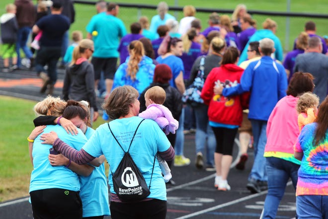 Families and friends comfort each other during the fourth annual Walk Into the Light for suicide awareness and prevention Sunday at Lee Stadium in Newcomerstown.