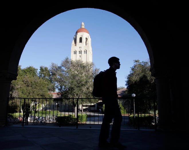 FILE - In this Feb. 15, 2012 file photo, a Stanford University student walks in front of Hoover Tower on the Stanford University campus in Palo Alto, Calif. Federal authorities have charged college coaches and others in a sweeping admissions bribery case in federal court. The racketeering conspiracy charges were unsealed Tuesday, March 12, 2019, against coaches at schools including Stanford, Wake Forest, Georgetown, the University of Southern California and the University of Southern California and University of California, Los Angeles. (AP Photo/Paul Sakuma, File)