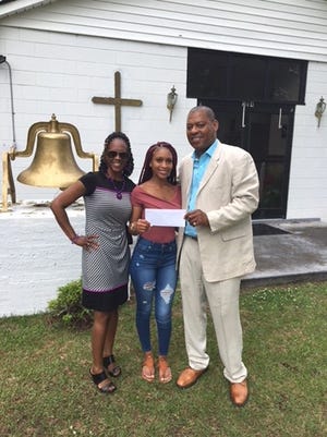 Pictured receiving the Hattie King Moore scholarship is Shamonia Freeland center, Orlander Moore right, and her mother, Pamela Freeland left.