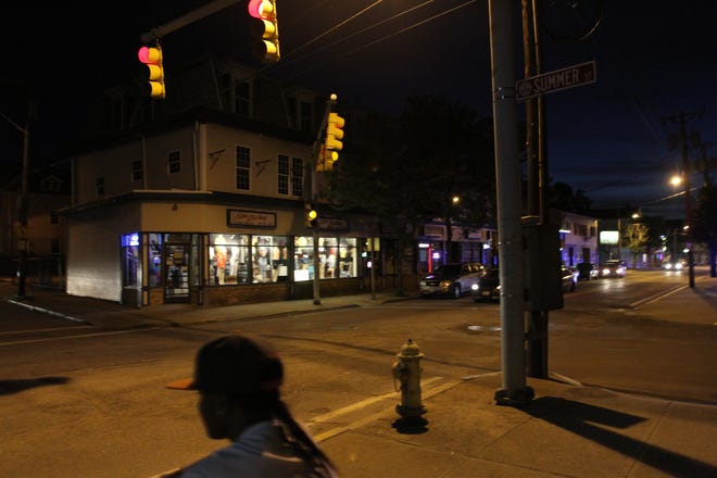 Dexter and Summer streets in Central Falls are almost empty, except for a cyclist peddling by, as the curfew goes into effect at 9:00 p.m. [The Providence Journal, file]