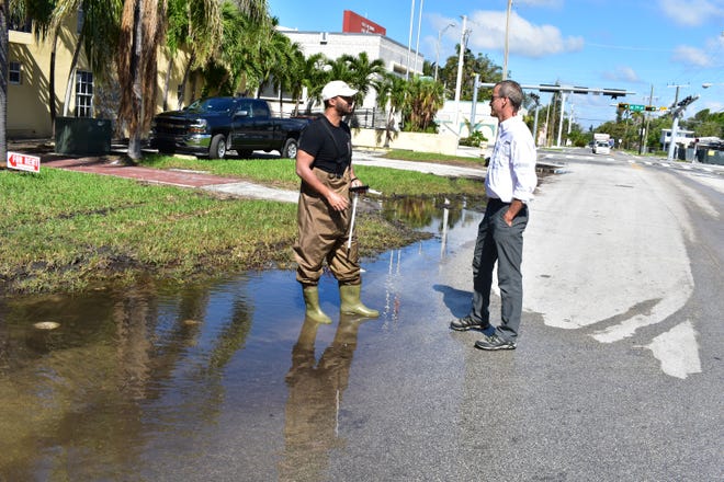 Steven Mcalpine with the New York-based First Street Foundation and Thomas Ruppert with Florida Sea Grant talk about flooding occurring in Florida as a result of rising seas. The men stand in a street flooded during a king tide in Miami Beach in November 2017. [Gatehouse Florida / Dinah Voyles Pulver]