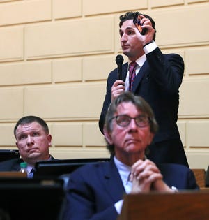 Rhode Island House Minority Leader Blake A. Filippi holds up his mobile phone as he addresses legislators during a late afternoon session on gaming at the State House in Providence, R.I., Tuesday, March 12, 2019. Rhode Island lawmakers gathered to discuss a bill to expand sports betting by offering mobile gaming. At foreground right is R.I. Rep. John W. Lyle Jr., at left is R.I. Rep. David Place. (AP Photo/Charles Krupa)
