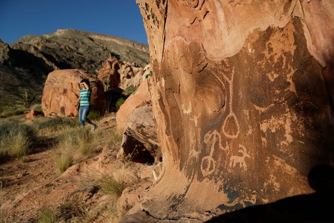 FILE - In this May 26, 2017, file photo, Susie Gelbart walks near petroglyphs at the Gold Butte National Monument near Bunkerville, Nev. As Democrats in Congress prepare to scrutinize President Donald Trump's review of 27 national monuments, most of the recommendations made by ex-Interior Ryan Zinke remain unfinished, seemingly stuck on the backburner as other matters consume the White House. Zinke recommended cuts to the boundaries of Gold Butte National Monument to free up a water district that he thought shouldn't have been included in the boundaries. (AP Photo/John Locher, File)