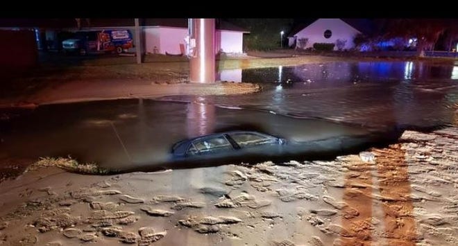 Florida Highway Patrol troopers said a DUI suspect hit a fire hydrant, causing a watery hole to open up and swallow the car, in Summerfield on Friday morning [Courtesy Marion County Fire Rescue]