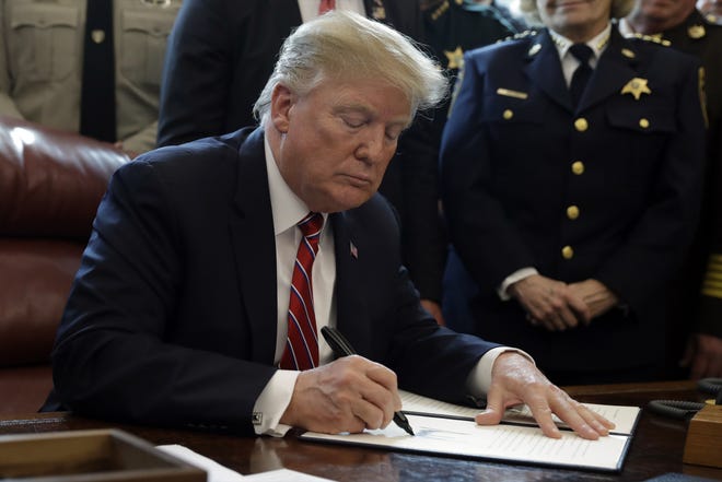 President Donald Trump signs the first veto of his presidency in the Oval Office of the White House, Friday, March 15, 2019, in Washington. Trump issued the first veto, overruling Congress to protect his emergency declaration for border wall funding. [AP Photo/Evan Vucci]