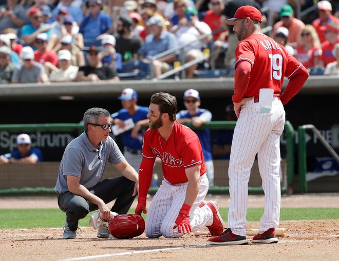 Philadelphia Phillies' Bryce Harper, center, yells toward Toronto Blue Jays pitcher Trent Thornton as manager Gabe Kapler, right, and assistant trainer Chris Mudd check on him after he was hit by a pitch during the sixth inning in a spring training baseball game, Friday. [YONG KIM / THE ASSOCIATED PRESS]
