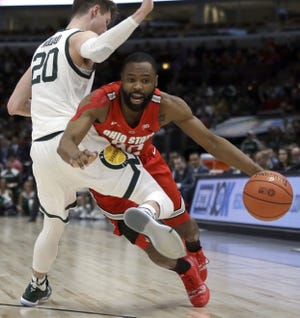 Ohio State's Keyshawn Woods drives against Michigan State's Matt McQuaid in Friday's game in the Big Ten tournament. Woods is hoping the Buckeyes' win over Indiana on Thursday tipped the scales in their favor for an NCAA Tournament spot. [Kiichiro Sato/The Associated Press]