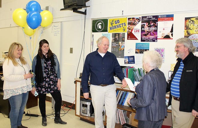 ArtWorks member Janet Lee hands David Boswell a letter announcing he was chosen as Artist of the Year as Connie Sexton, Sarah Walworth and Keith Rushing look on during a surprise presentation Thursday at Hillsdale High School. [NANCY HASTINGS/Hillsdale Daily News]
