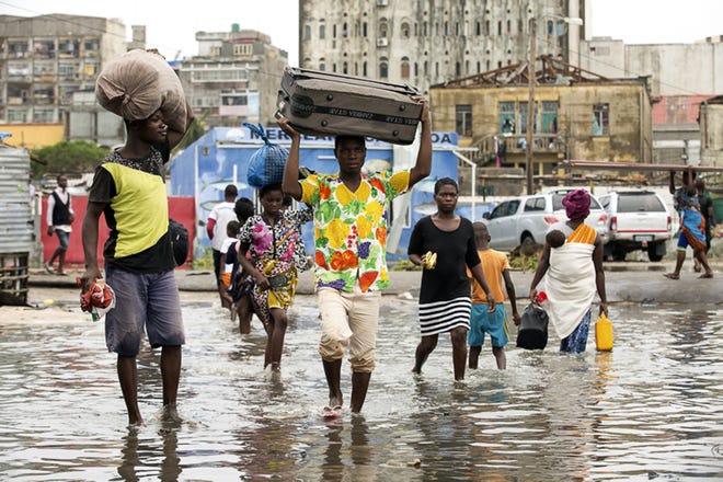 In this photo taken on Friday, March 15, 2019 and provided by the International Red Cross, people carry their personal effects after Tropical Cyclone Idai, in Beira, Mozambique. Mozambique's President Filipe Nyusi says that more than 1,000 may have by killed by Cyclone Idai, which many say is the worst in more than 20 years. Speaking to state Radio Mozambique, Nyusi said Monday, March 18 that although the official death count is currently 84, he believes the toll will be more than 1,000. (Denis Onyodi/IFRC via AP)
