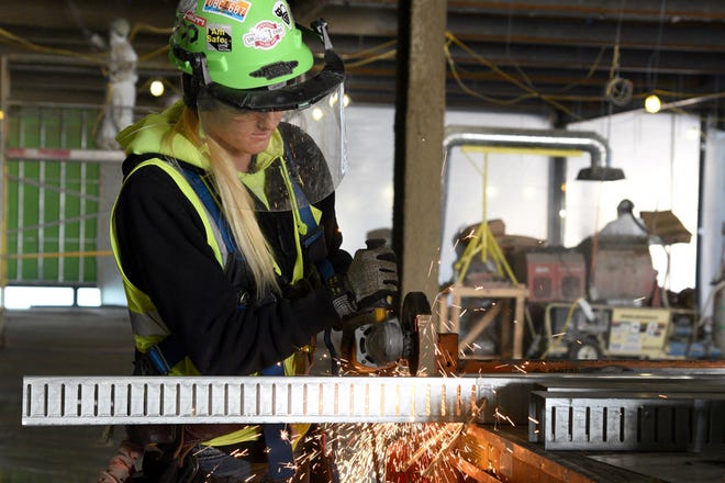 Using an angle grinder, Natalya Groff, a construction worker for Ohio Ceiling and Partition (OCP), cuts a metal stud. The Ottawa Lake resident is working on the site of the new ProMedica Charles and Virginia Hickman Hospital in Adrian.