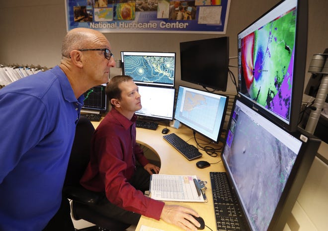National Hurricane Center senior hurricane specialists Lixion Avila, left, and Dan Brown track the status of Hurricane Michael on Oct. 10 at the National Hurricane Center in Miami. At least two early predictions are calling for a near normal to below normal 2019 hurricane season. [Wilfredo Lee/The Associated Press]