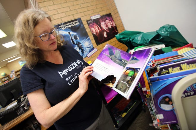 Township Three Elementary School librarian Sandra Ross shows how military books are in bad shape at the school's library on Tuesday. A donation in memory of the late Dennis Hamrick will pay for new military books. [Brittany Randolph/The Star]
