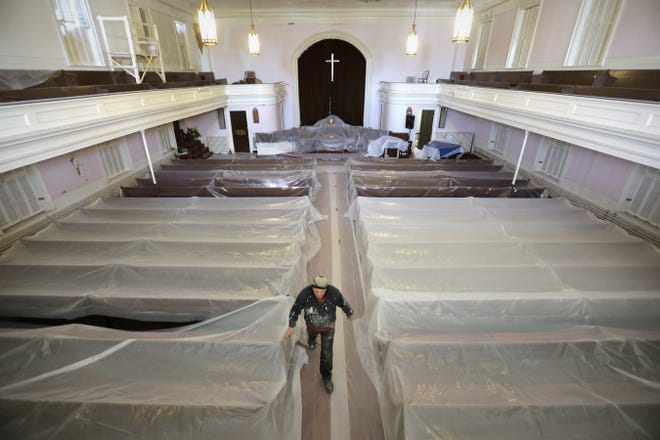 The pews are covered in plastic for protection as Charles Hauck walks down the aisle of the central section of the First Baptist Church on William Street. [PETER PEREIRA/THE STANDARD-TIMES]