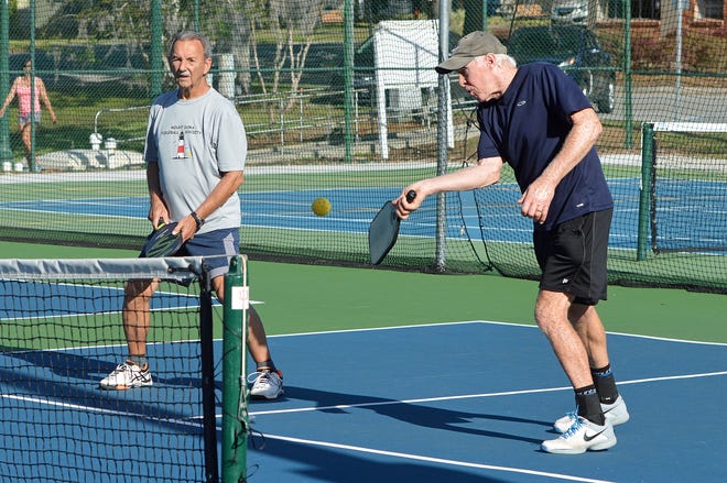 A man hits the ball over the net as his partner looks on during a game of pickleball on the courts at Donnelly Park in downtown Mount Dora. [Whitney Lehnecker/Daily Commercial]