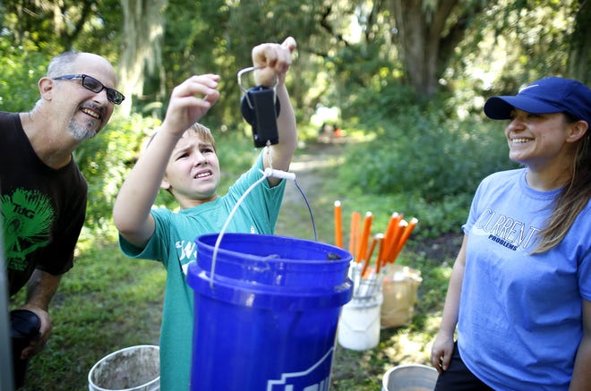 Volunteer Maxwell Burger, 11, weighs a bucket of trash that was collected during a cleanup. [Gatehouse Media File]