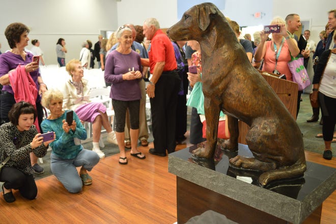People take photos of a statue memorializing Ponce, a 9-month-old black Labrador retriever who police say was found beaten to death in a Ponce Inlet home in 2017. The statue was unveiled at a ceremony in October at the Town of Ponce Inlet Community Center. [News-Journal File/Casmira Harrison]