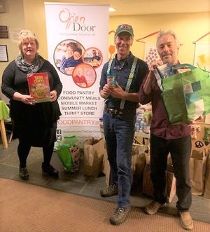 Julie LaFontaine, executive director for The Open Door, Rev. Bradford Clark and Orville Giddings, stand amid food donations brought in at the ShamRock & Roll, a St. Patrick’s Day celebration and food drive for The Open Door featuring music from the Orville Giddings Band. [Courtesy photo]