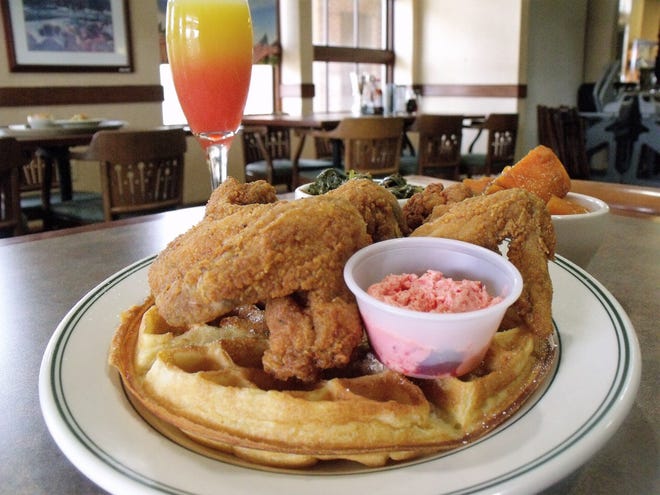 Chicken and waffles is the star attraction at Uptown's Chicken and Waffles, which opened in February on Bragg Boulevard. They are shown with a side of homemade collards, candied yams and the house signature beverage, the blushing mimosa. [Alison Minard for The Fayetteville Observer]