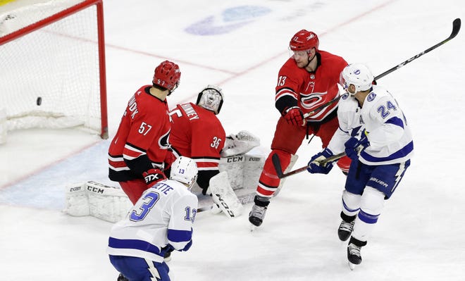 Tampa Bay Lightning's Ryan Callahan scores against Carolina Hurricanes goalie Curtis McElhinney (35) while Hurricanes' Trevor van Riemsdyk (57) and Warren Foegele (13) defend during the third period in Raleigh, on Thursday. [AP Photo/Gerry Broome]