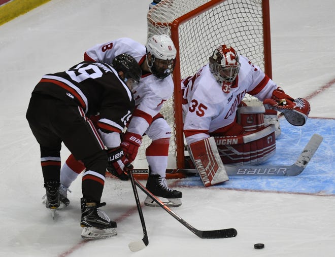 Cornell's Yanni Kaldis tries to keep Brown's Alex Brink from reaching a loose puck while Big Red goaltender Matthew Galajda protects the short side of the net during the third period of Friday's ECAC semifinal game at the Olympic Center. Cornell won, 6-0, and advanced to Saturday's final.  [Adirondack Daily Enterprise / Lou Reuter]