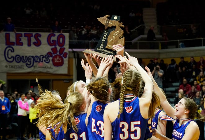 The Lenawee Christian girls basketball team raises the Division 4 state championship trophy after beating St. Ignace, 48-46, at Calvin College.