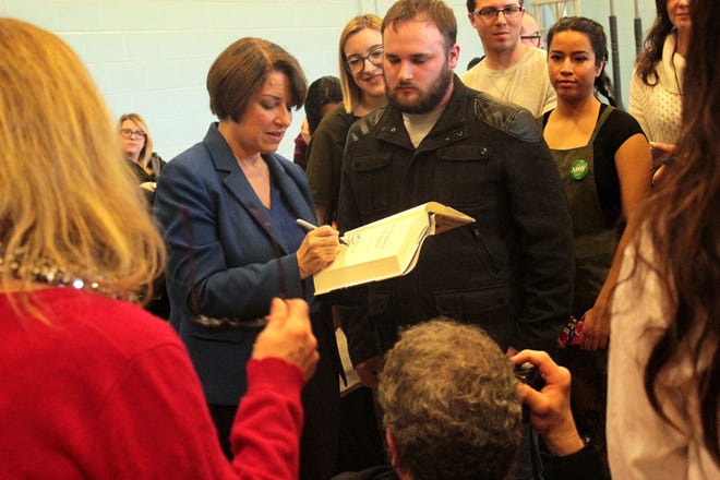 U.S. Sen. Amy Klobuchar, D-Minnesota, signs a copy of one of her books following her presidential campaign appearance at Rye Junior High School on Saturday. [Erin Hayes photo]