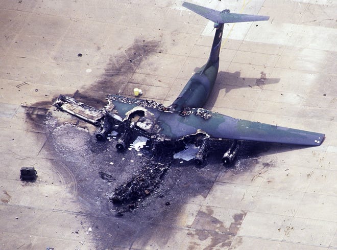 The burned frame of a C-141 Starlifter aircraft lays on Pope Air Force Base the day after an F-16 in flight collided with a C-130 airfraft, that then crashed into this C-141 at Green Ramp ten years ago. [File/aerial photo by Marcus Castro]