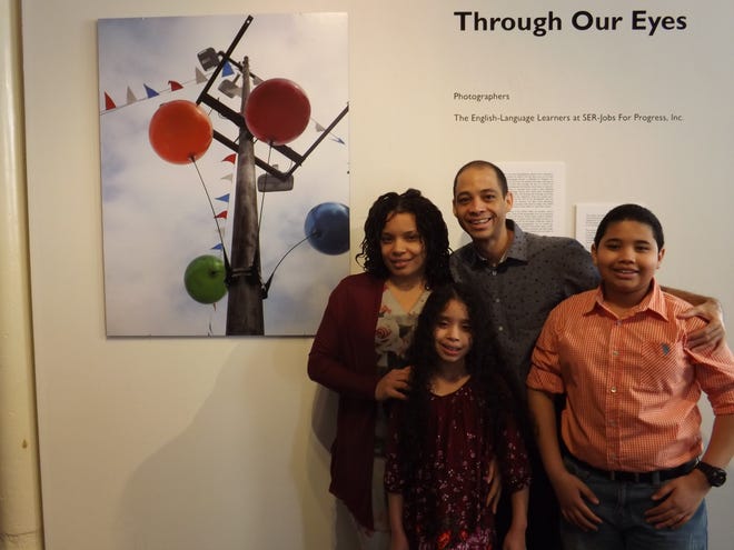 Johani Artache stands with her husband, Jose Gonzalez, and their children, Joseann and Joseany beside the photograph she had displayed at the "Through Our Eyes" art exhibit in Fall River on Saturday. [Herald News Photo | Peter Jasinski]