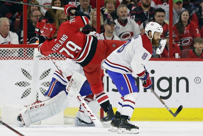 Carolina's Micheal Ferland trips in front of Montreal goalie Carey Price as Canadiens' Jordie Benn skates past during Sunday's game in Raleigh. The Hurricanes won in overtime and moved closer to clinching a playoff spot. [Gerry Broome/The Associated Press]
