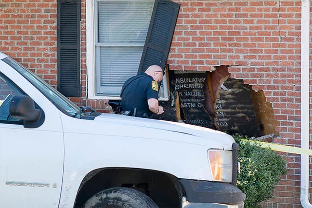 INVESTIGATION — An officer with the Asheboro Police Department observes the damages an apartment sustained when a truck hit the building Saturday afternoon. (Scott Pelkey / The Courier-Tribune)