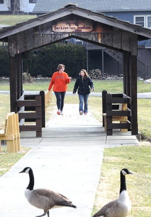 Melissa Lashley, left, and Kelly Costello take a stroll around the pond at Jackson Park one morning last week. A couple of geese managed to make their way into the foreground of the photo.